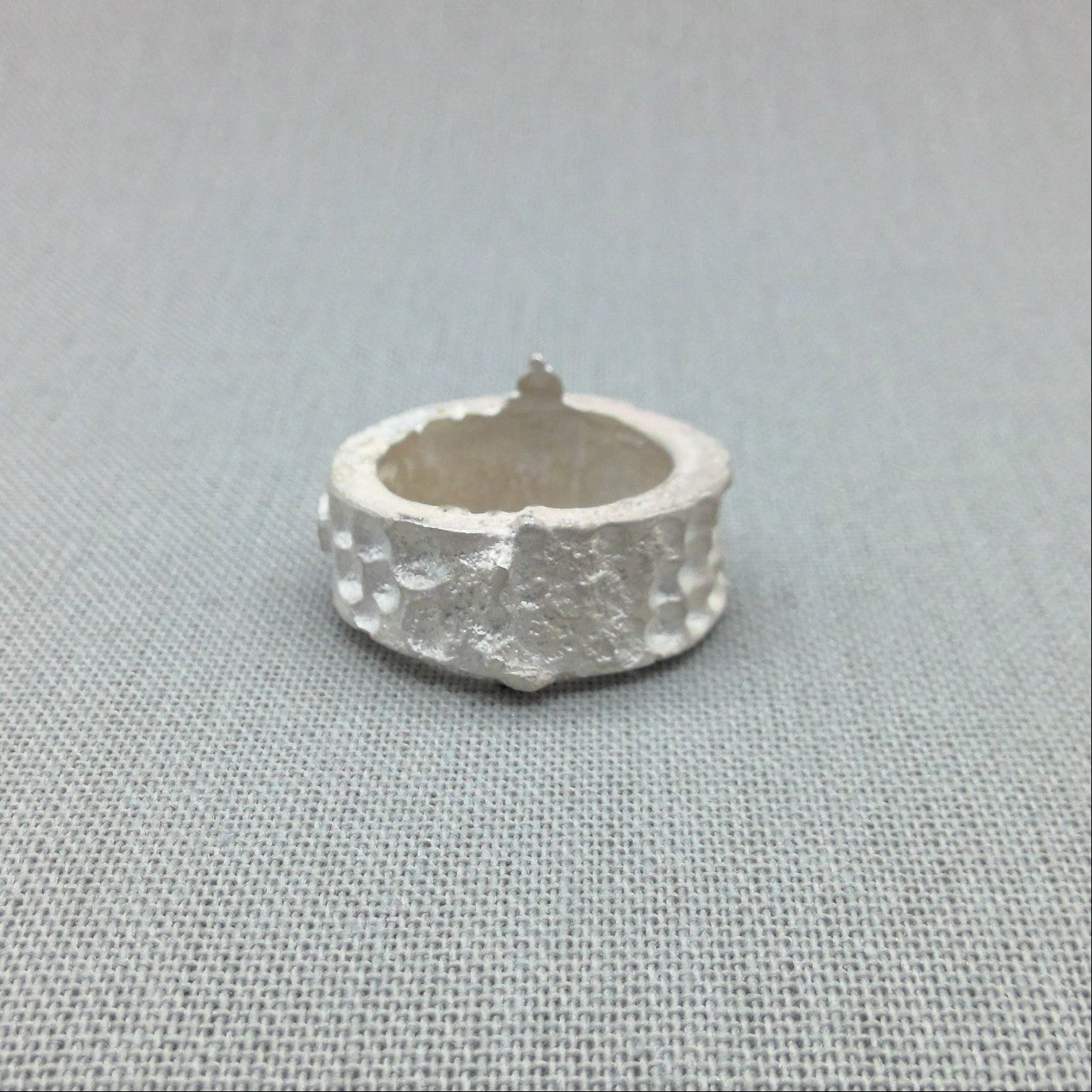 Textured silver ring, architectural relic design, close-up