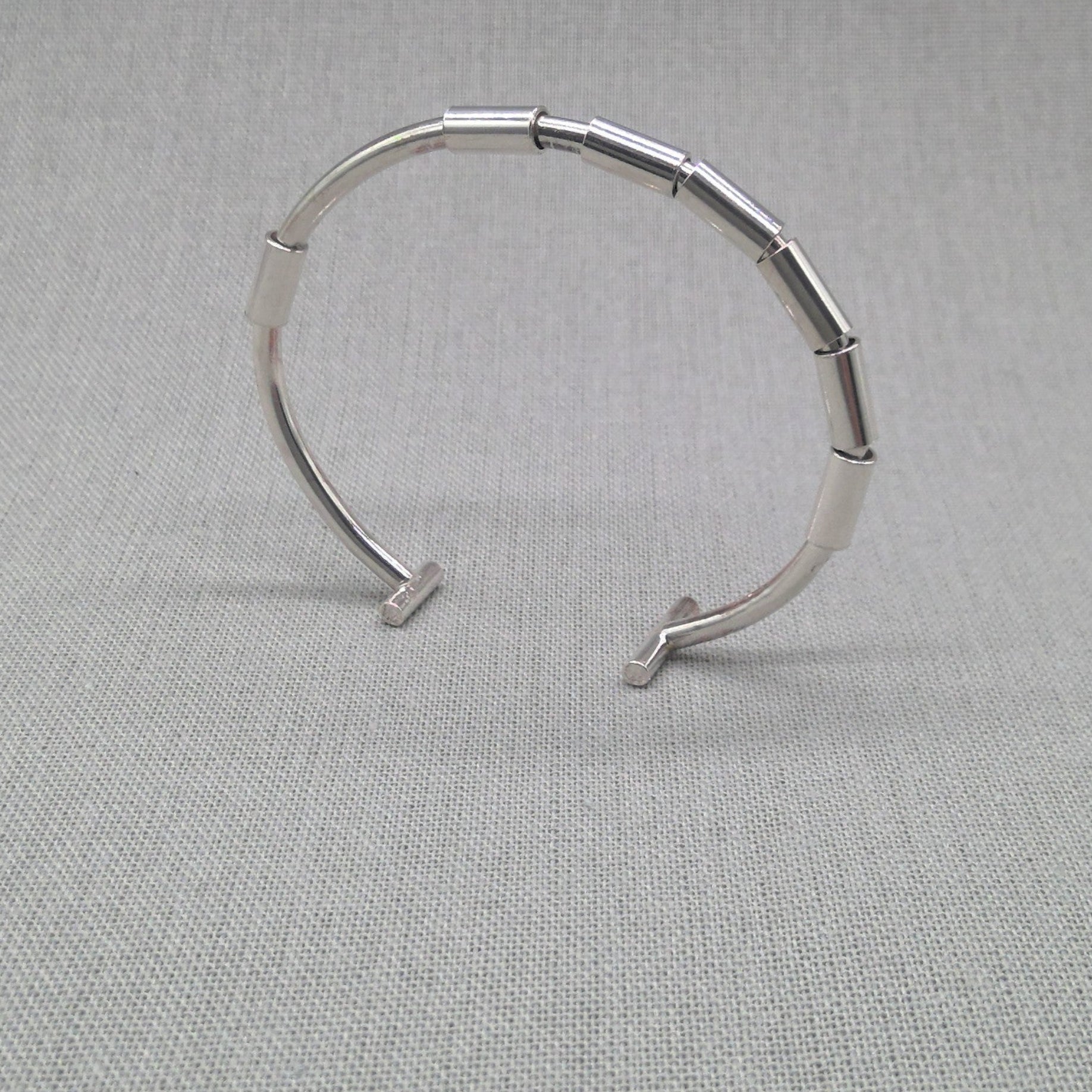 Recycled silver segmented open bangle with jointed links on fabric