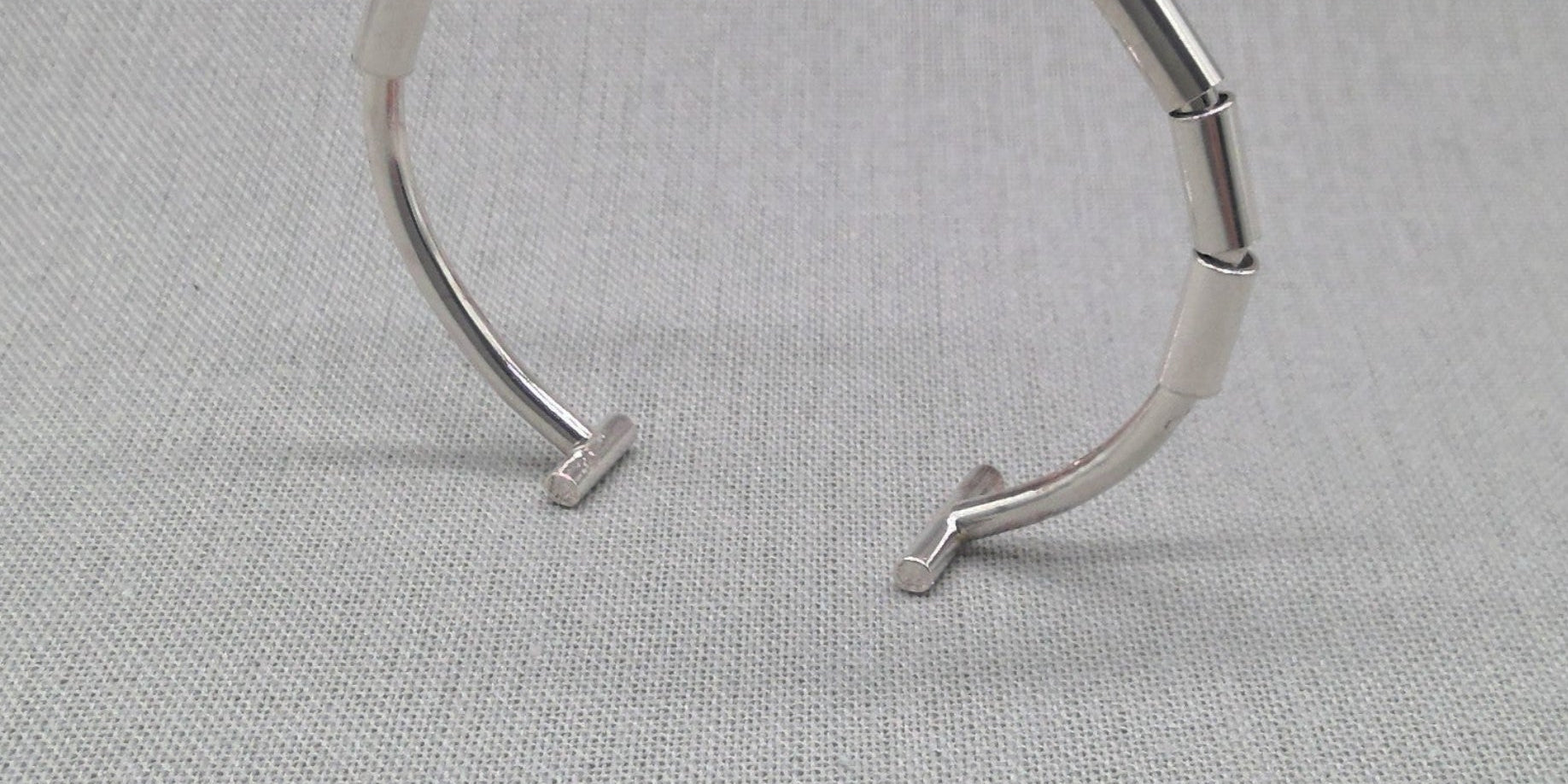Recycled silver segmented open bangle with jointed links on fabric
