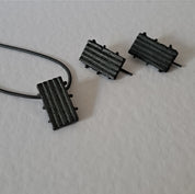 Handcrafted black oxidised sterling silver jewellery set featuring a sculptural pendant and matching stud earrings with a contemporary architectural design.