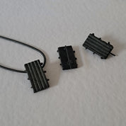 Handcrafted black oxidised sterling silver jewellery set featuring a sculptural pendant and matching stud earrings with a contemporary architectural design.