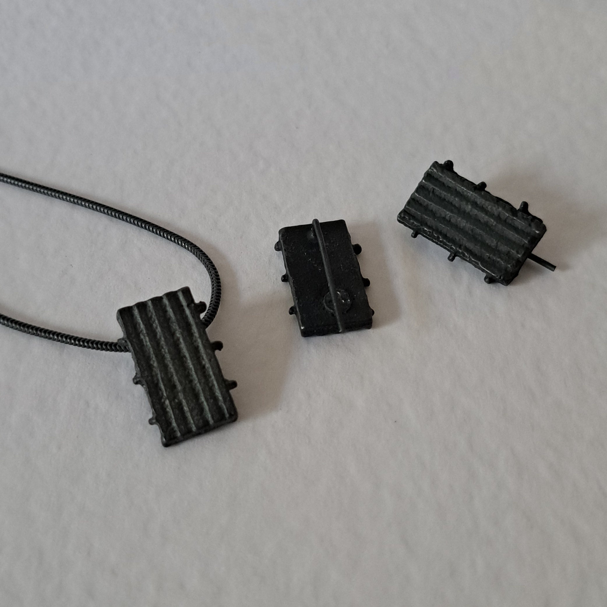 Handcrafted black oxidised sterling silver jewellery set featuring a sculptural pendant and matching stud earrings with a contemporary architectural design.