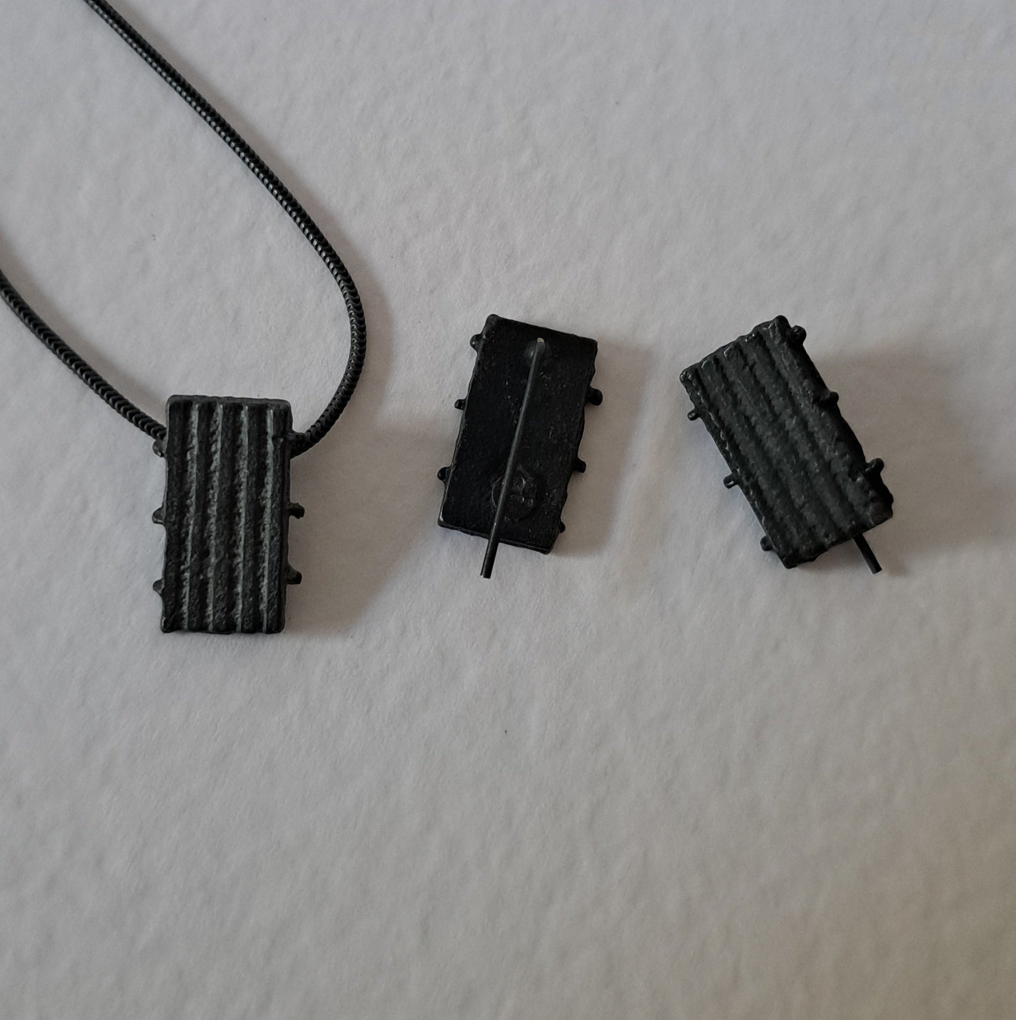 Handcrafted black oxidised sterling silver jewellery set featuring a sculptural pendant and matching stud earrings with a contemporary architectural design.