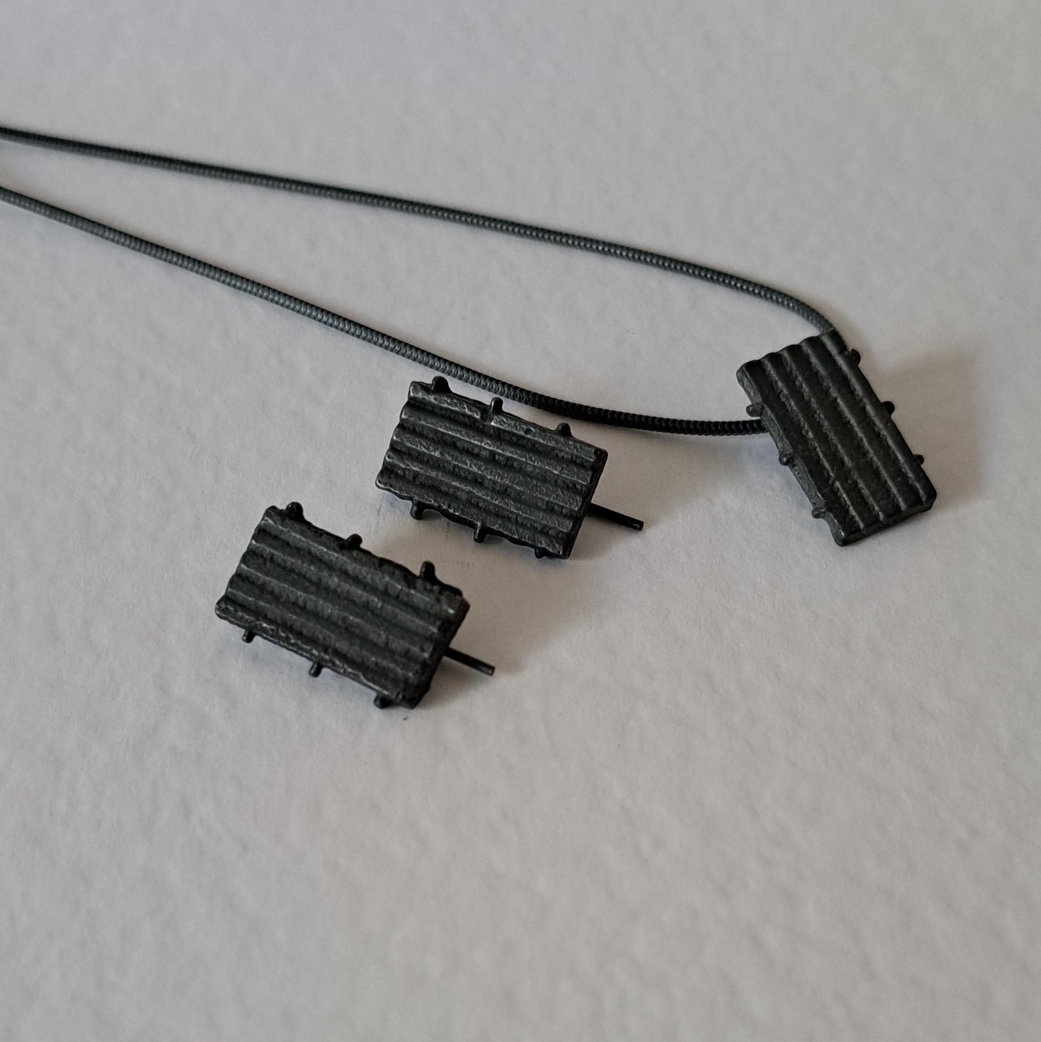 Handcrafted black oxidised sterling silver jewellery set featuring a sculptural pendant and matching stud earrings with a contemporary architectural design.