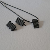 Handcrafted black oxidised sterling silver jewellery set featuring a sculptural pendant and matching stud earrings with a contemporary architectural design.