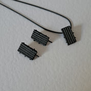 Handcrafted black oxidised sterling silver jewellery set featuring a sculptural pendant and matching stud earrings with a contemporary architectural design.