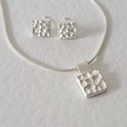 Handcrafted MINI sterling silver jewellery set featuring a sculptural textured pendant on a snake chain with matching stud earrings inspired by architecture.