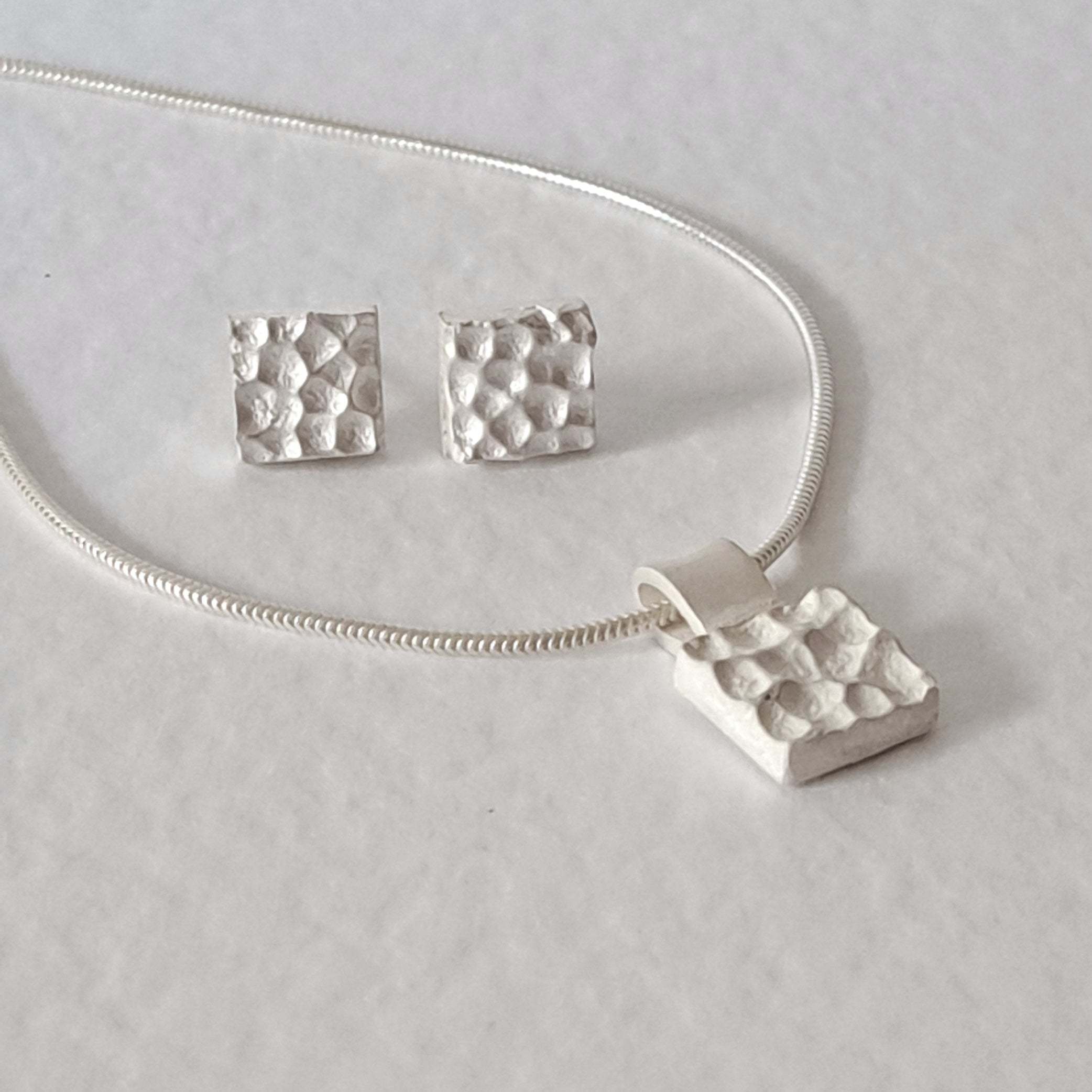 Handcrafted MINI sterling silver jewellery set featuring a sculptural textured pendant on a snake chain with matching stud earrings inspired by architecture.