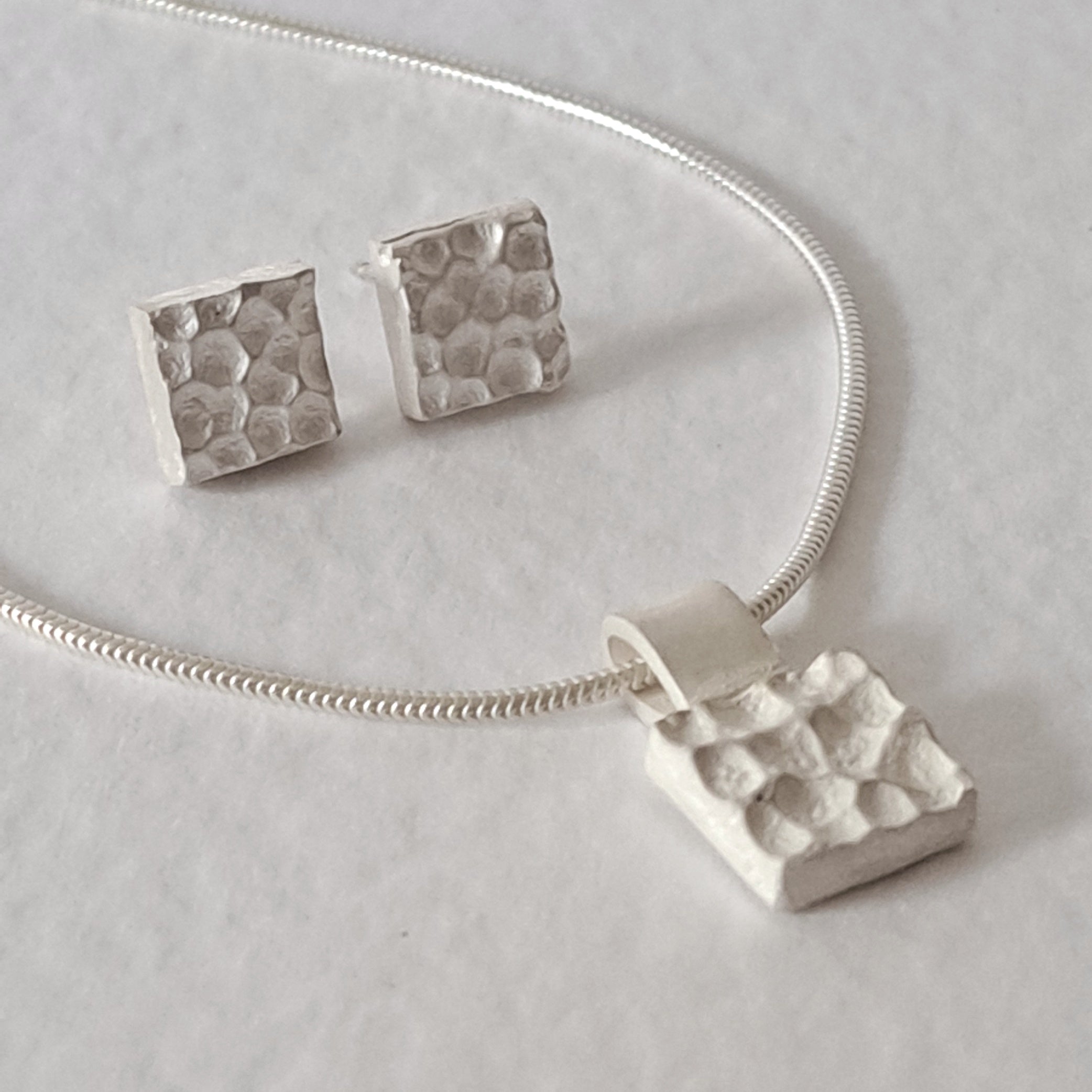 Handcrafted MINI sterling silver jewellery set featuring a sculptural textured pendant on a snake chain with matching stud earrings inspired by architecture.