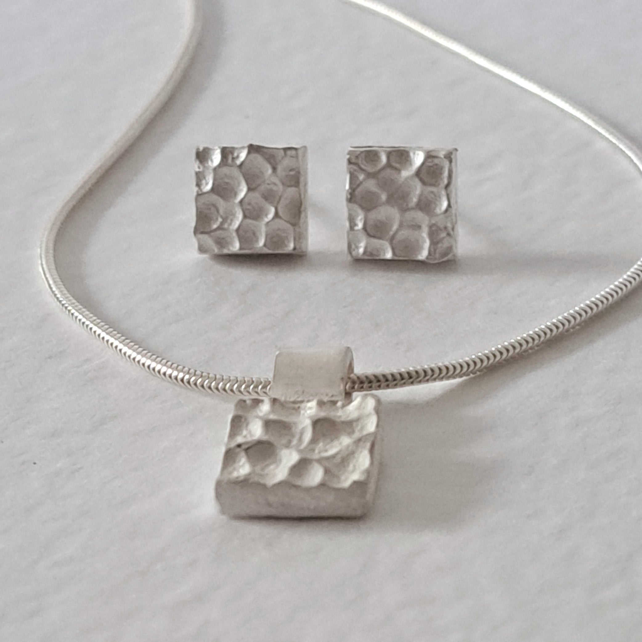 Handcrafted MINI sterling silver jewellery set featuring a sculptural textured pendant on a snake chain with matching stud earrings inspired by architecture.