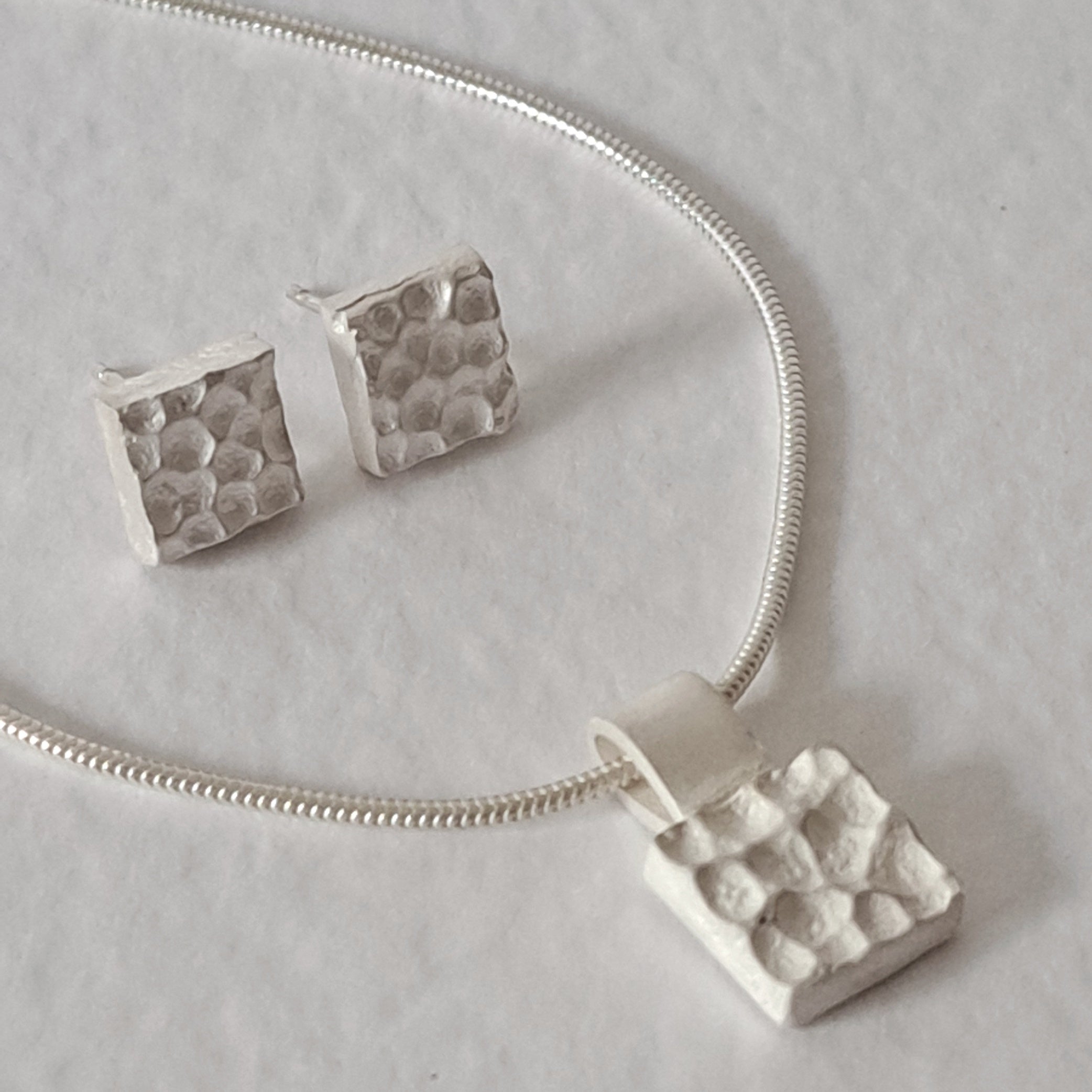 Handcrafted MINI sterling silver jewellery set featuring a sculptural textured pendant on a snake chain with matching stud earrings inspired by architecture.