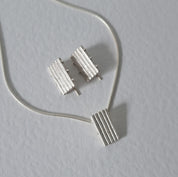 Handcrafted MINI sterling silver jewellery set featuring a sculptural pendant and matching stud earrings with an architectural linear texture.