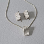 Handcrafted MINI sterling silver jewellery set featuring a sculptural pendant and matching stud earrings with an architectural linear texture.