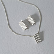 Handcrafted MINI sterling silver jewellery set featuring a sculptural pendant and matching stud earrings with an architectural linear texture.