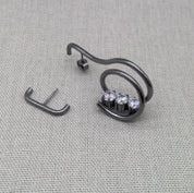 Angled view of coiled zircon earring and bar earring in oxidized silver