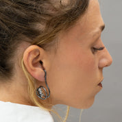 Model wearing asymmetrical oxidized silver zircon earring, side profile