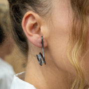Close-up of model wearing asymmetrical silver zircon earrings on ear