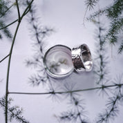 Close-up of hammered wedding rings against natural branch backdrop