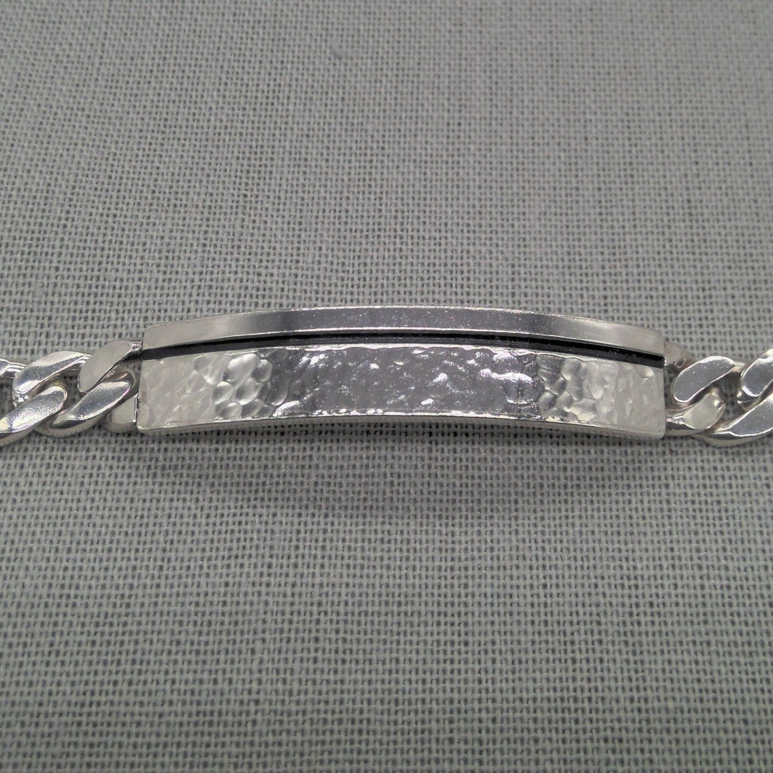 Angled view of recycled silver ID bracelet plaque and chain detail