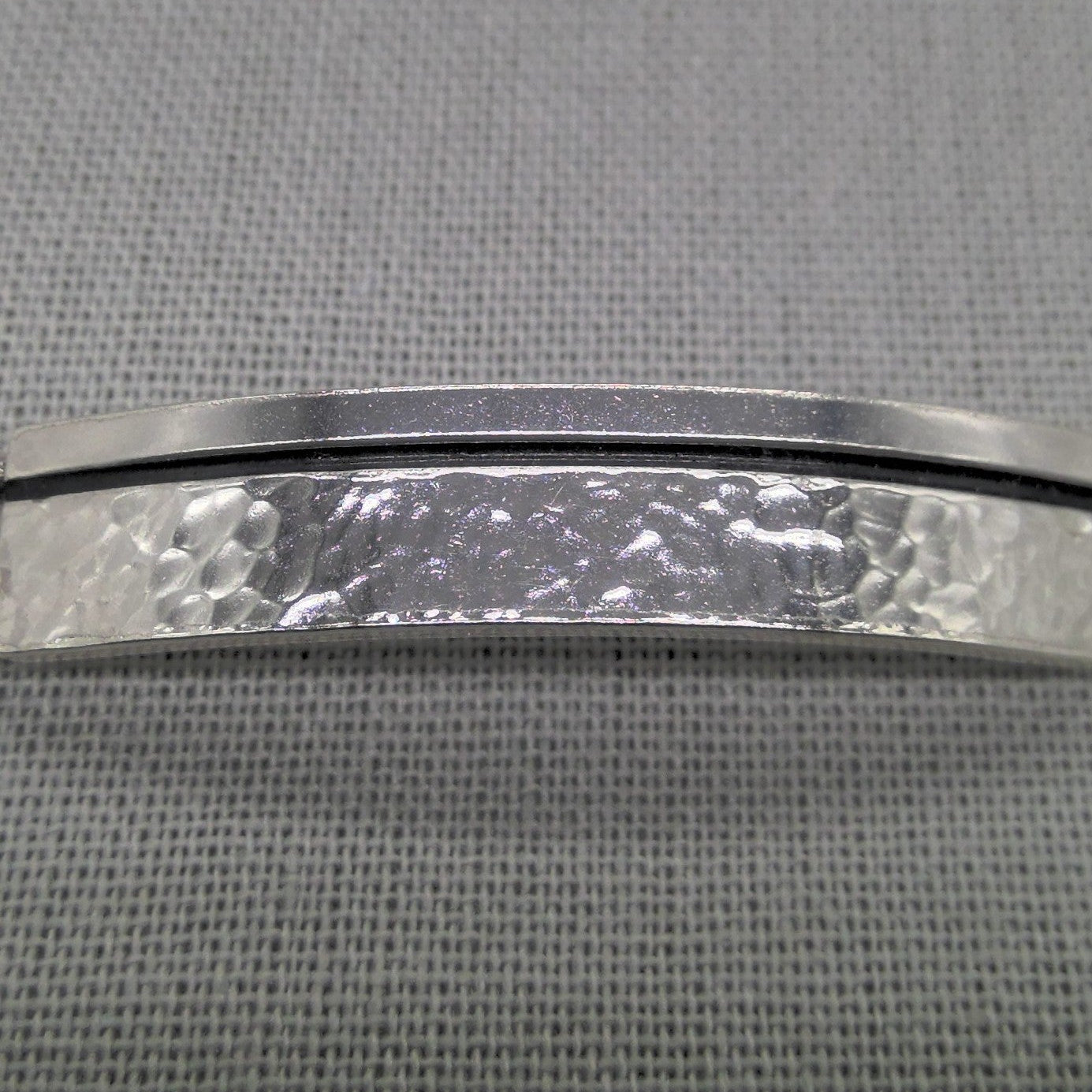 Close-up of hammered silver ID plaque on chunky curb chain bracelet
