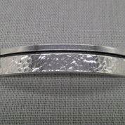 Close-up of hammered silver ID plaque on chunky curb chain bracelet
