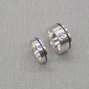 Angled view of hammered silver wedding ring set showing dark centre band