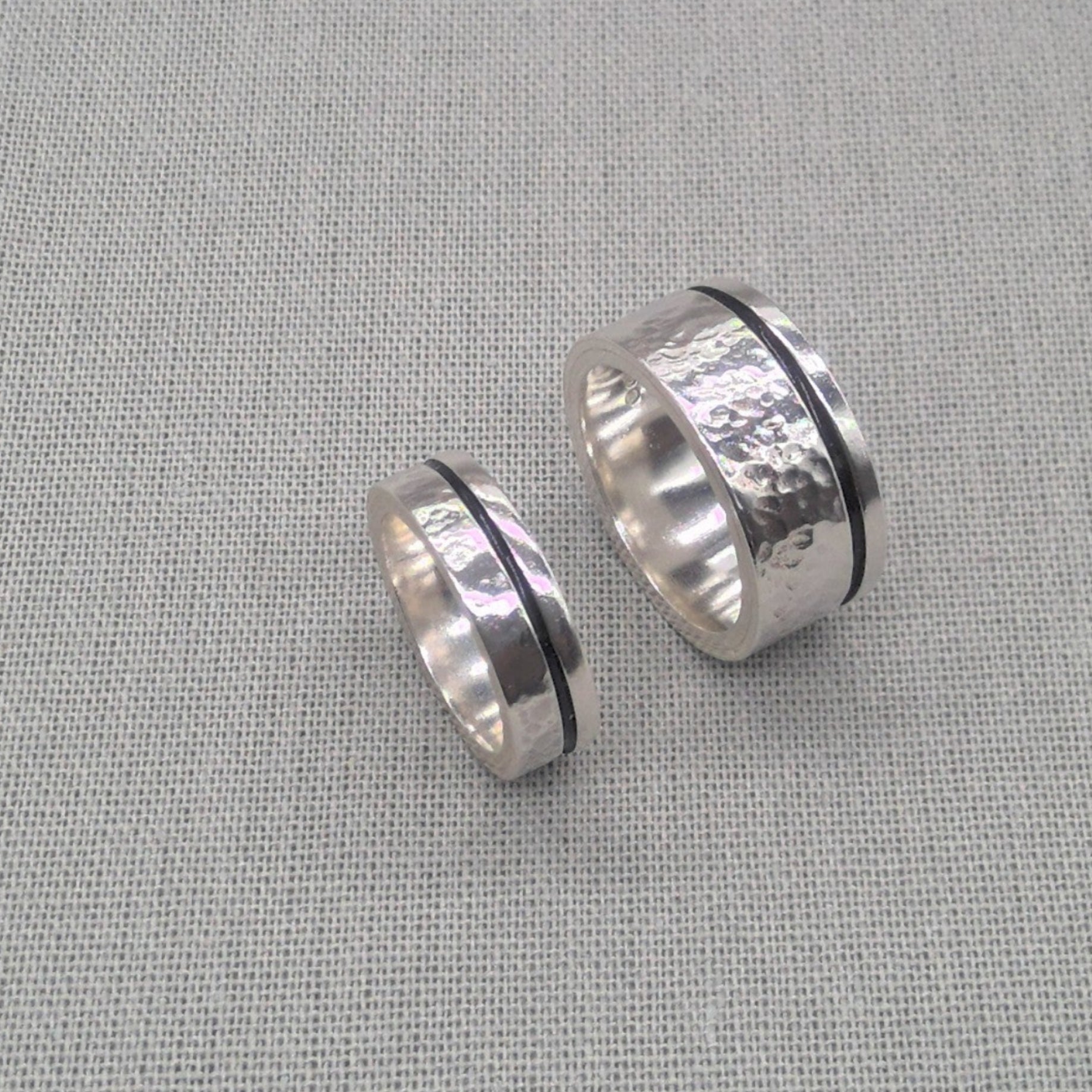 Angled view of hammered silver wedding ring set showing dark centre band