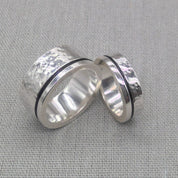 Pair of hammered recycled silver wedding rings leaning together