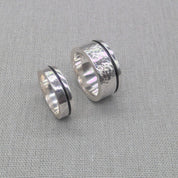 Side view of two chunky recycled silver wedding rings with hammered texture