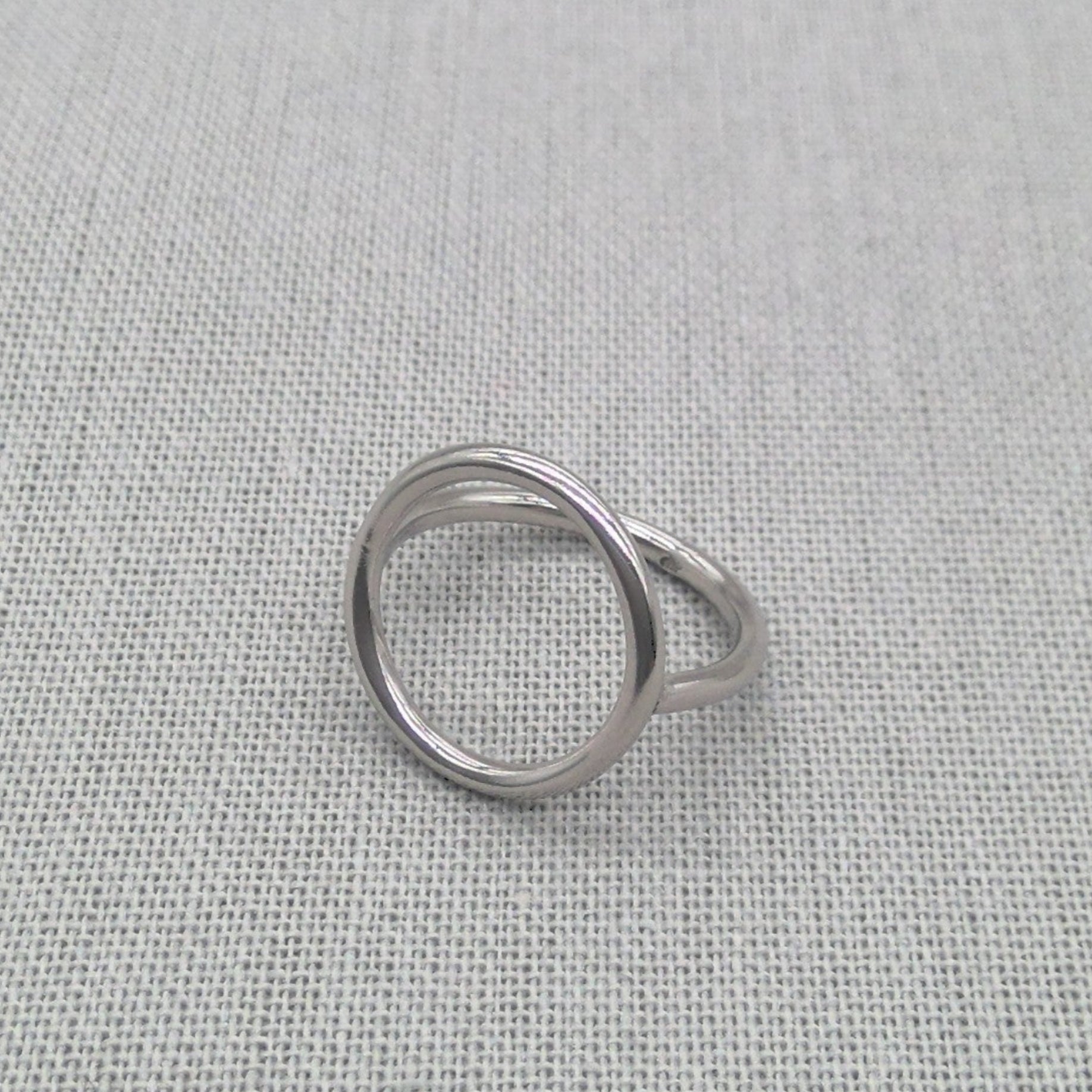 Angled view of polished silver sculptural circle ring