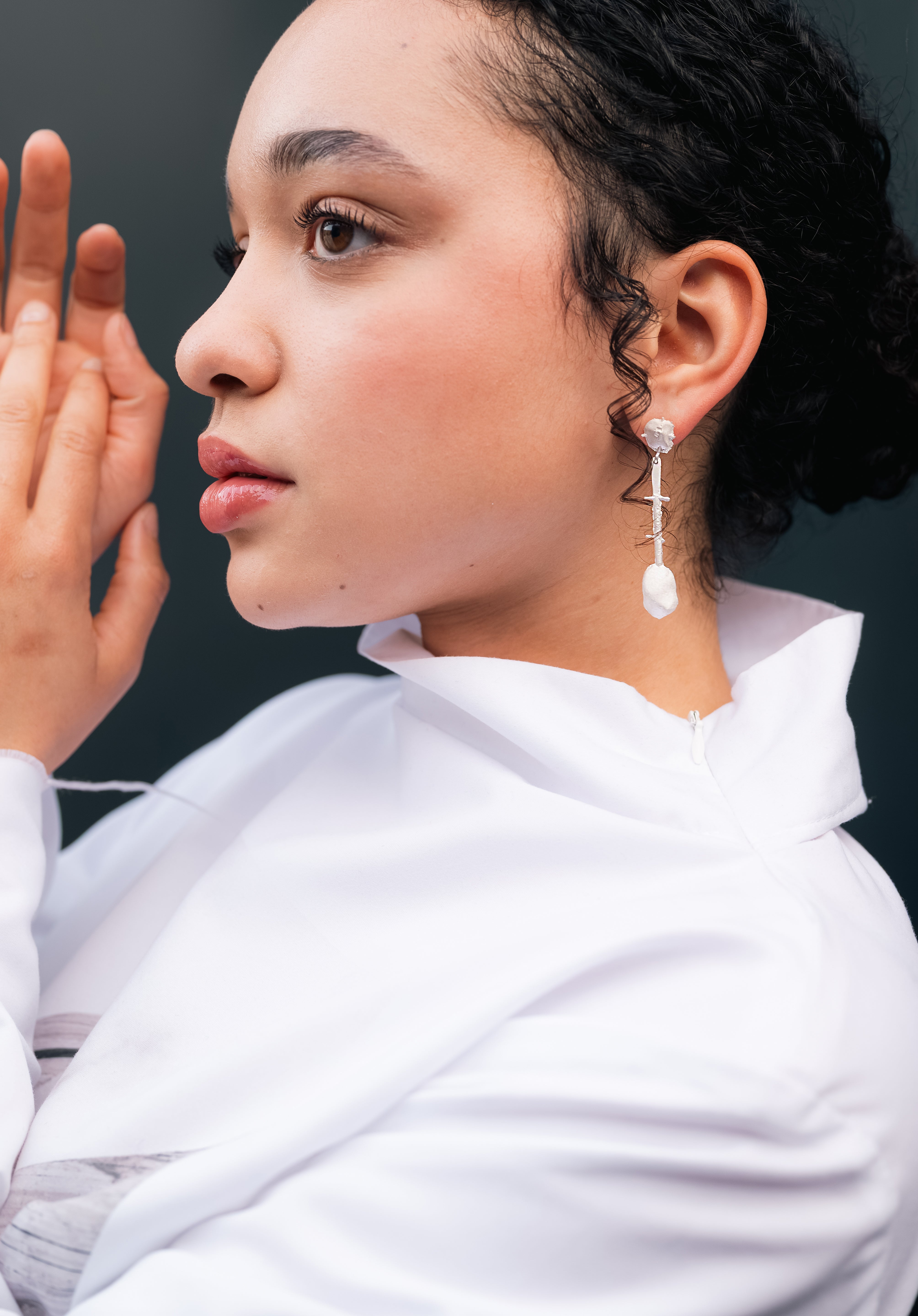 Woman wearing architectural drop earrings, side profile