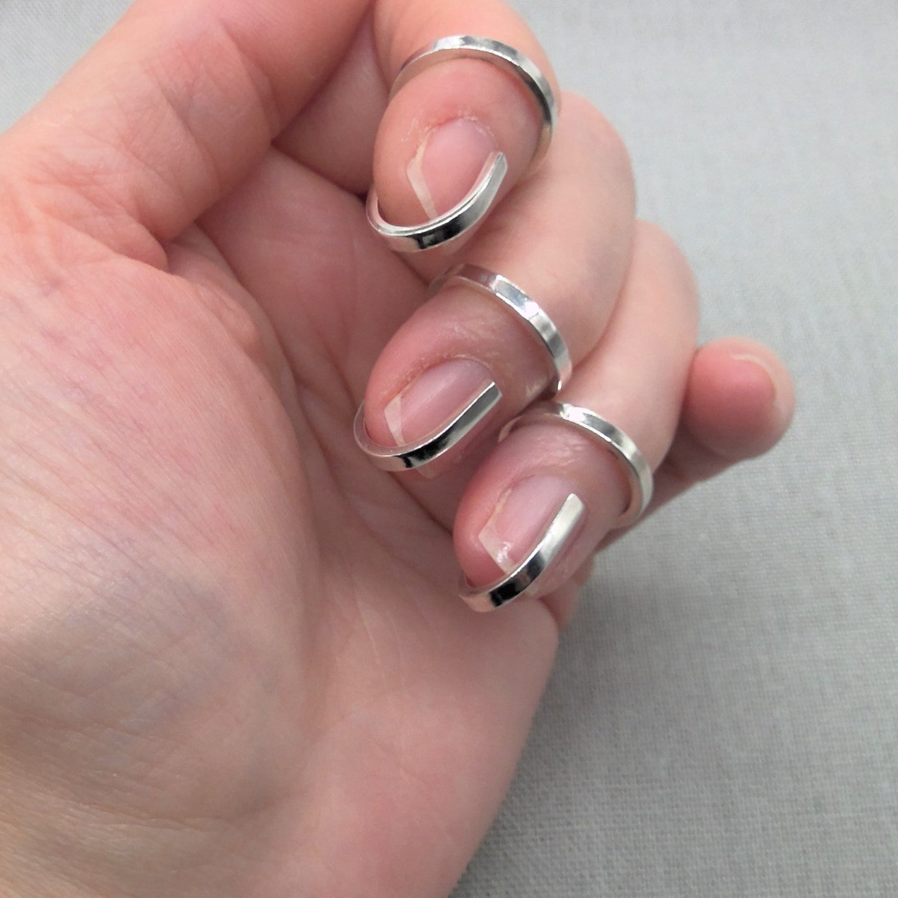 Hand wearing three Gladiator collection recycled silver wrap rings