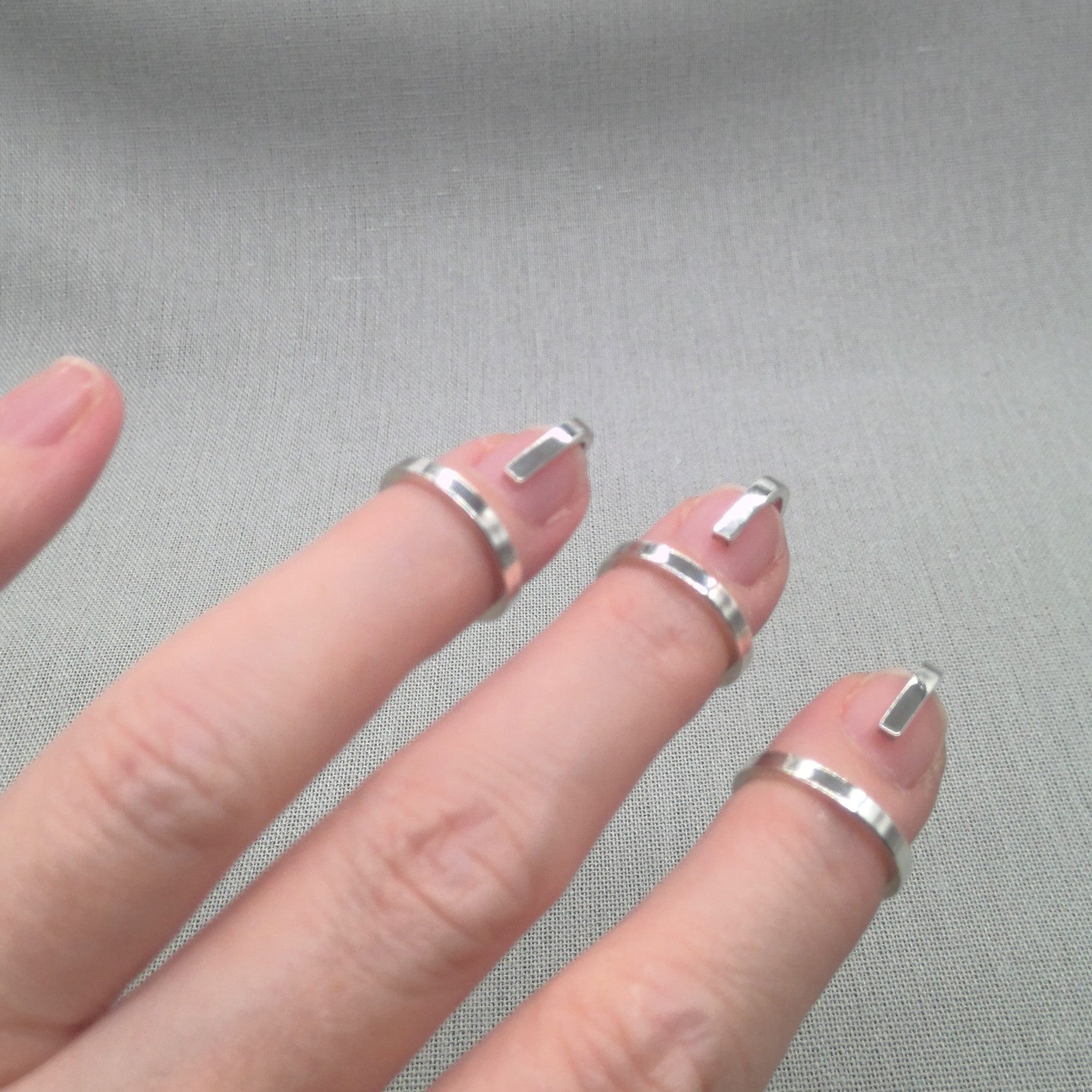 Close-up of fingers wearing Gladiator recycled silver wrap rings