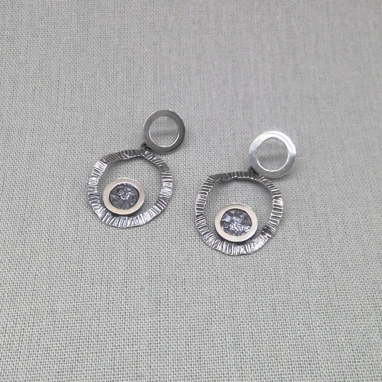 Hammered recycled silver double circle earrings with zircon centre on fabric