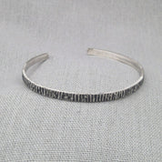 Hammered recycled silver cuff bangle with textured finish on fabric