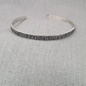 Side angle view of hammered recycled silver bangle showing texture