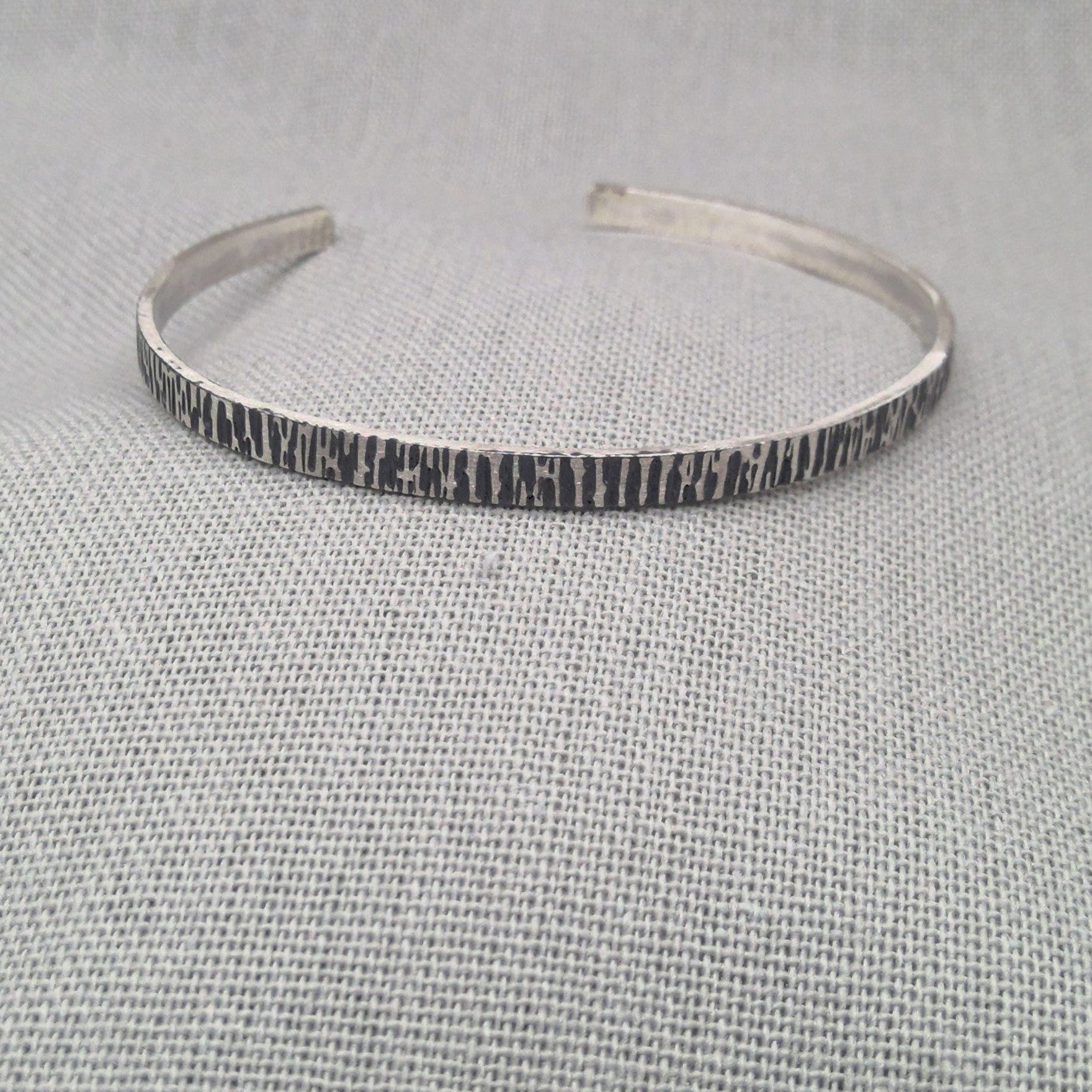 Side angle view of hammered recycled silver bangle showing texture