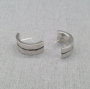 Angled view of open hammered silver ear cuffs with textured finish