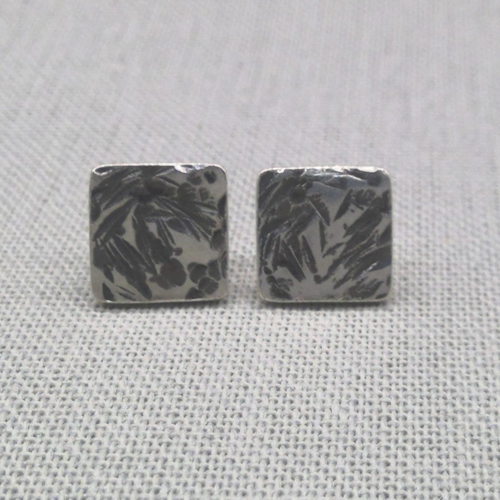 Textured hammered square recycled silver stud earrings on fabric