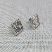Front view of square recycled silver studs with leaf-like hammered pattern