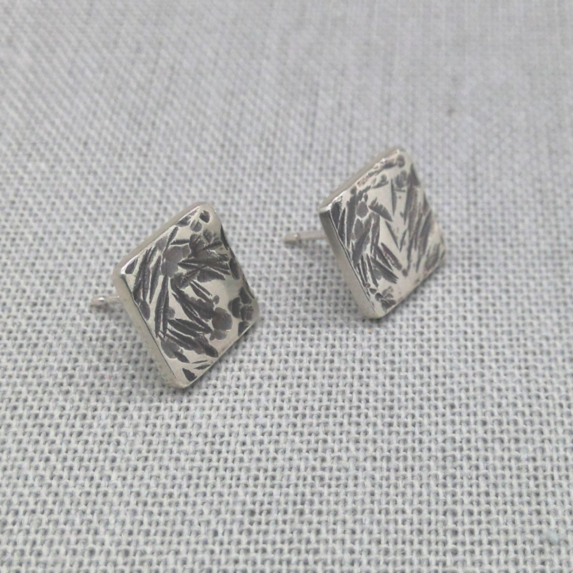 Front view of square recycled silver studs with leaf-like hammered pattern