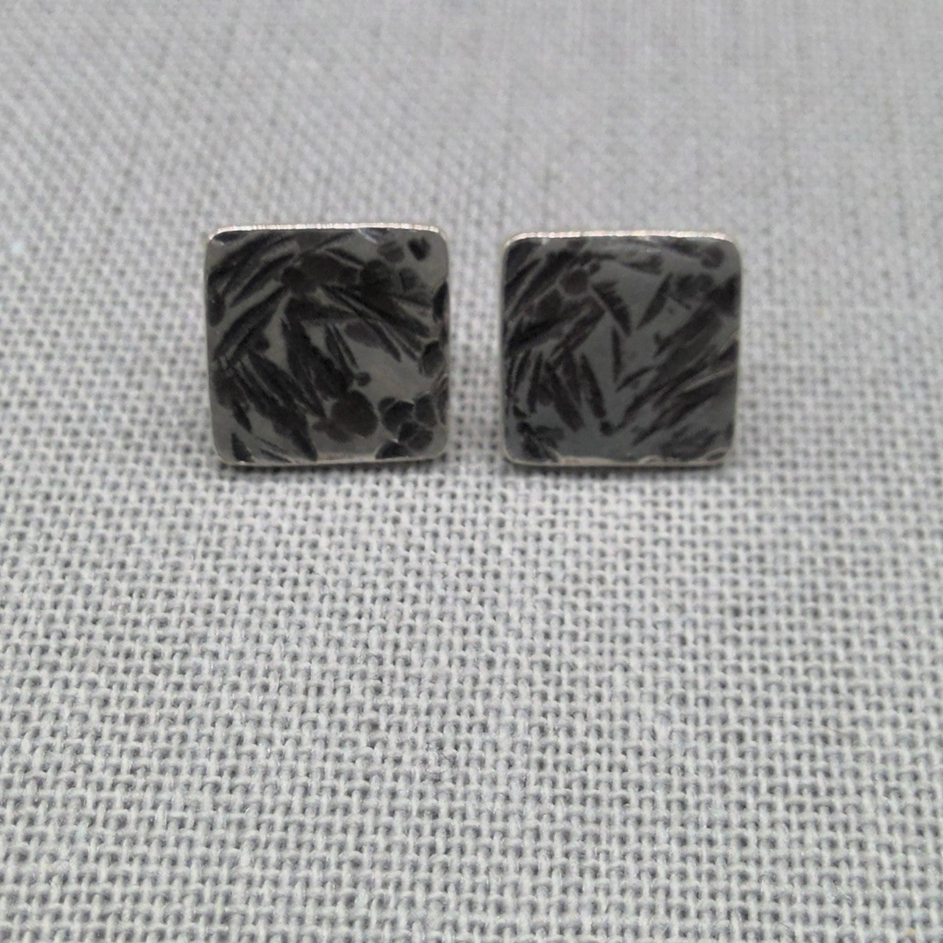Close-up of oxidized hammered texture on square recycled silver studs