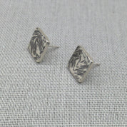 Side angle view of hammered square silver studs showing texture