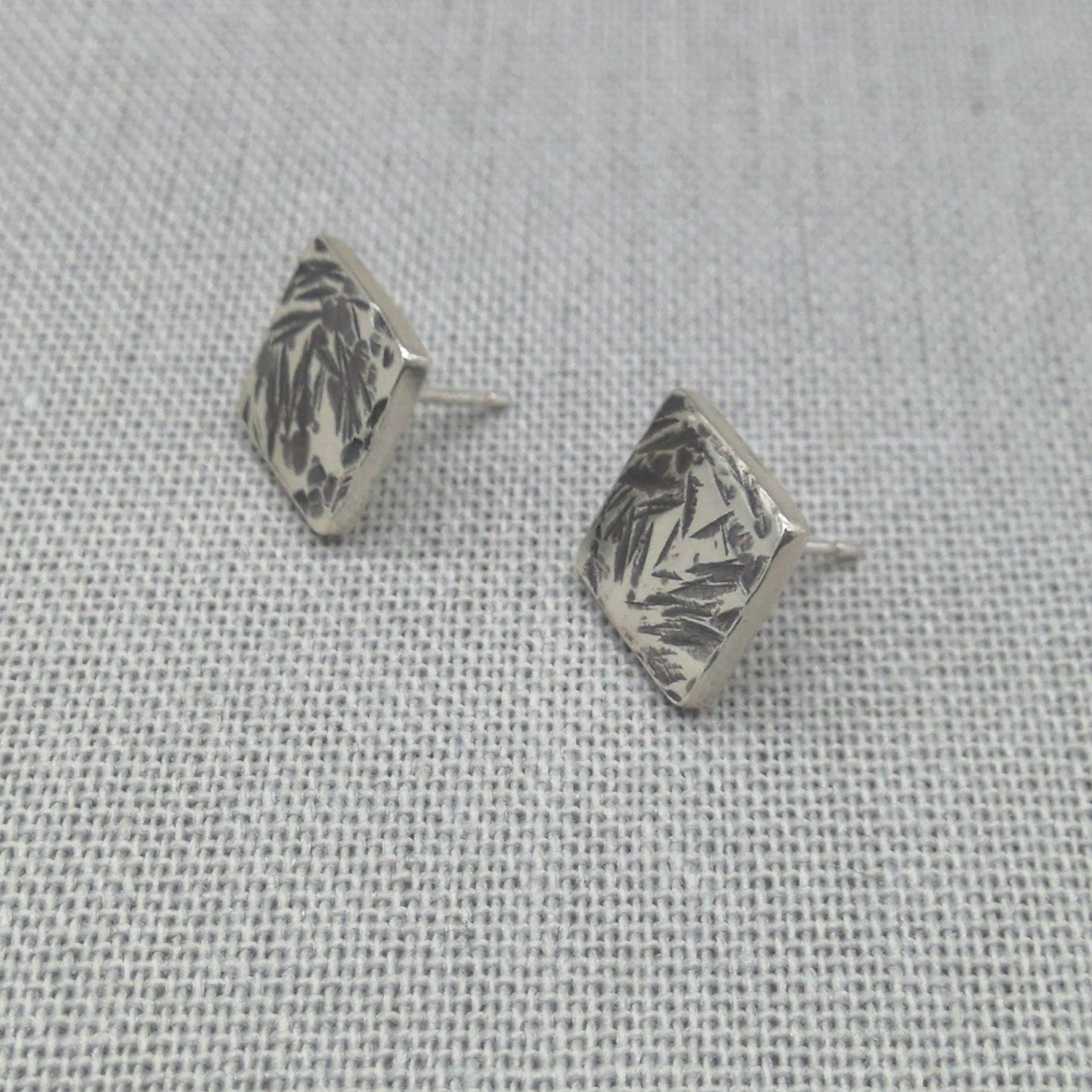 Side angle view of hammered square silver studs showing texture