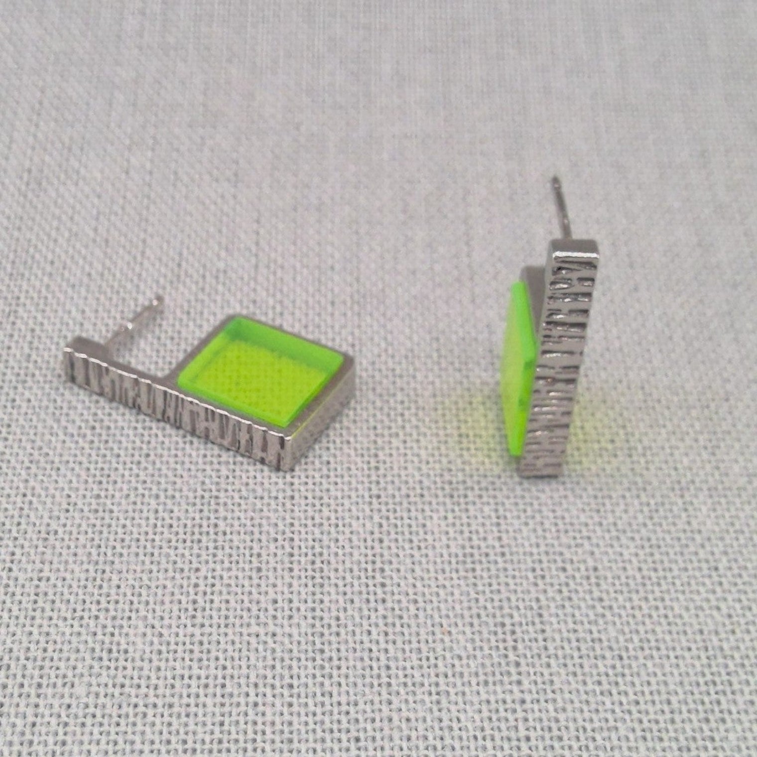 Close-up of neon green Perspex panel on hammered silver earring