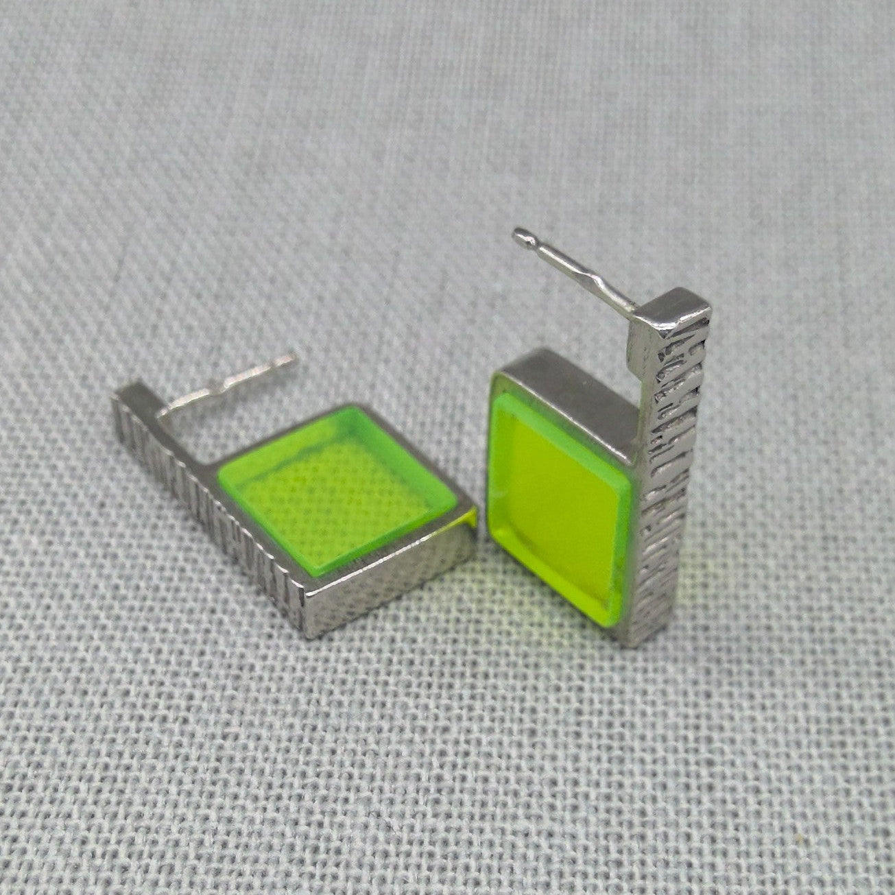 Angled view of neon green hammered silver earring pair