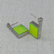 Angled view of neon green hammered silver earring pair