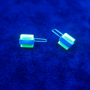 Close-up of neon Perspex stud earrings glowing under UV light