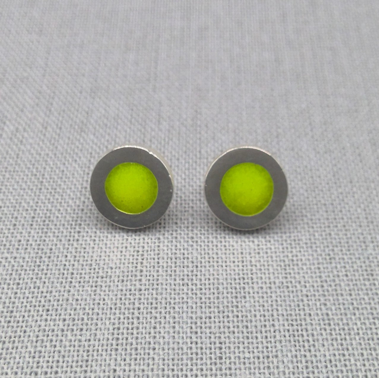 Close-up of green neon resin recycled silver stud earrings