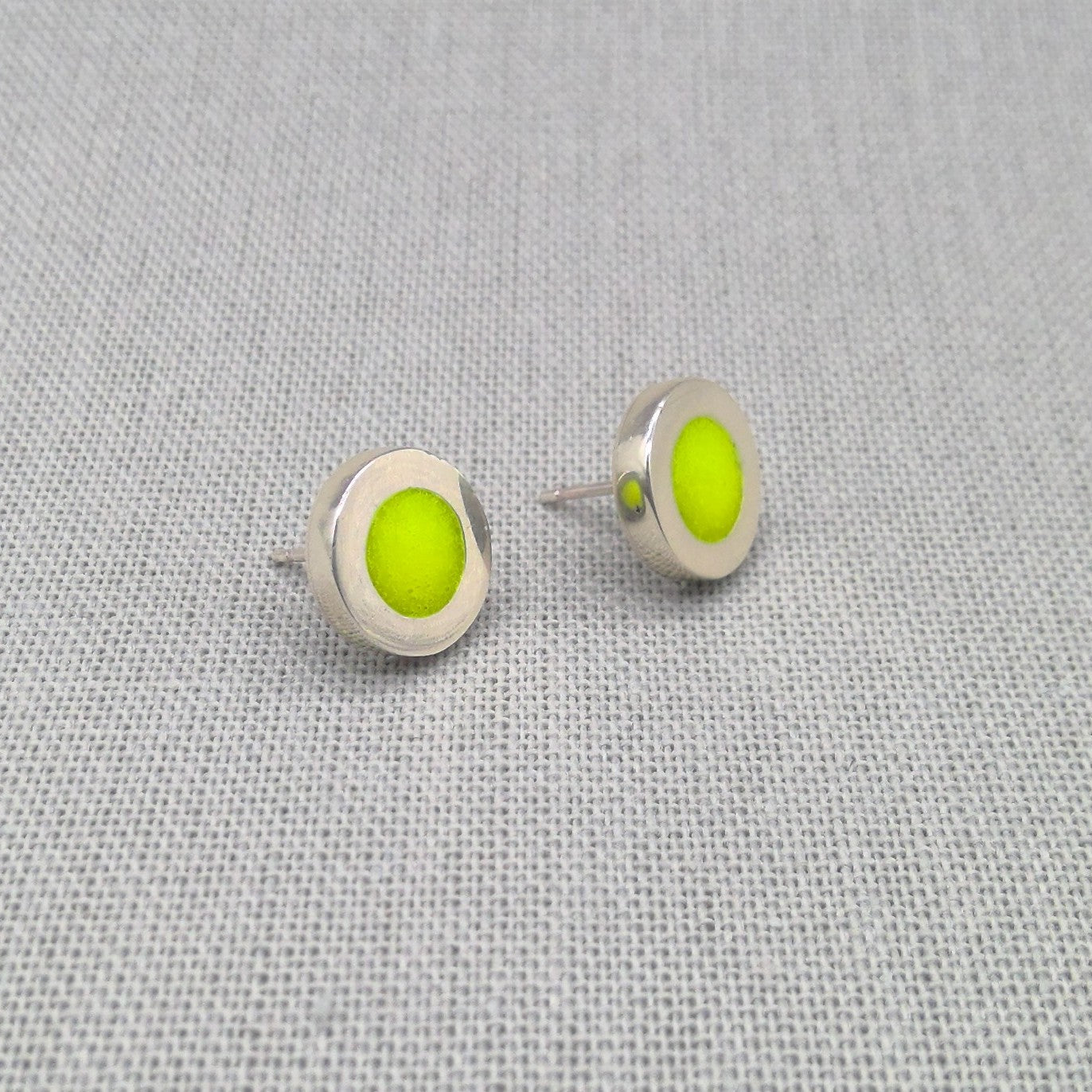 Close-up of yellow neon resin recycled silver stud earrings